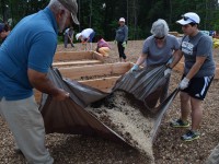 Volunteers toss and turn elements to make enriched soil for the garden.