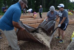 Volunteers toss and turn elements to make enriched soil for the garden.