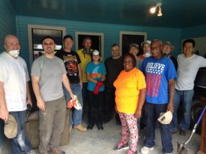 From left are Michael Lenahan, Nathan Reid, Garrett Coffee, Glenn Urquhart, Christian Tracy, Kelly Ladd, Bill Bentley, Minho Park, and gather around Ruthie and David of Baton Rouge in the garage of the home they are restoring after the floods. They group spent the morning tearing down damaged kitchen and bathroom cabinets.